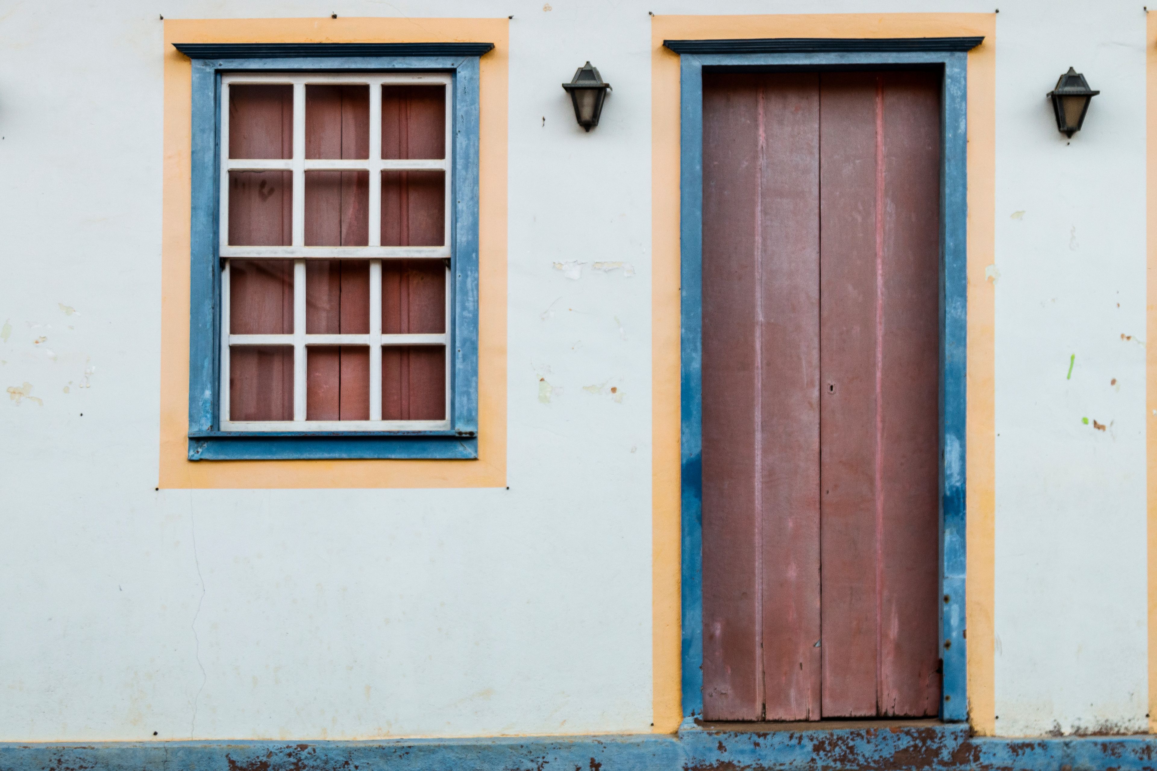 Um edifício com uma janela e uma porta, ambos com detalhes azuis.
