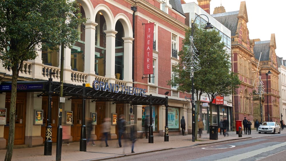 The Grand Theatre building with a red banner, trees, and a street scene.