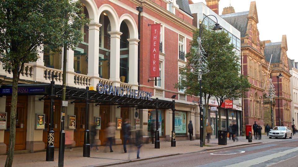 L'edificio del Grand Theatre con uno striscione rosso, alberi e una scena di strada.