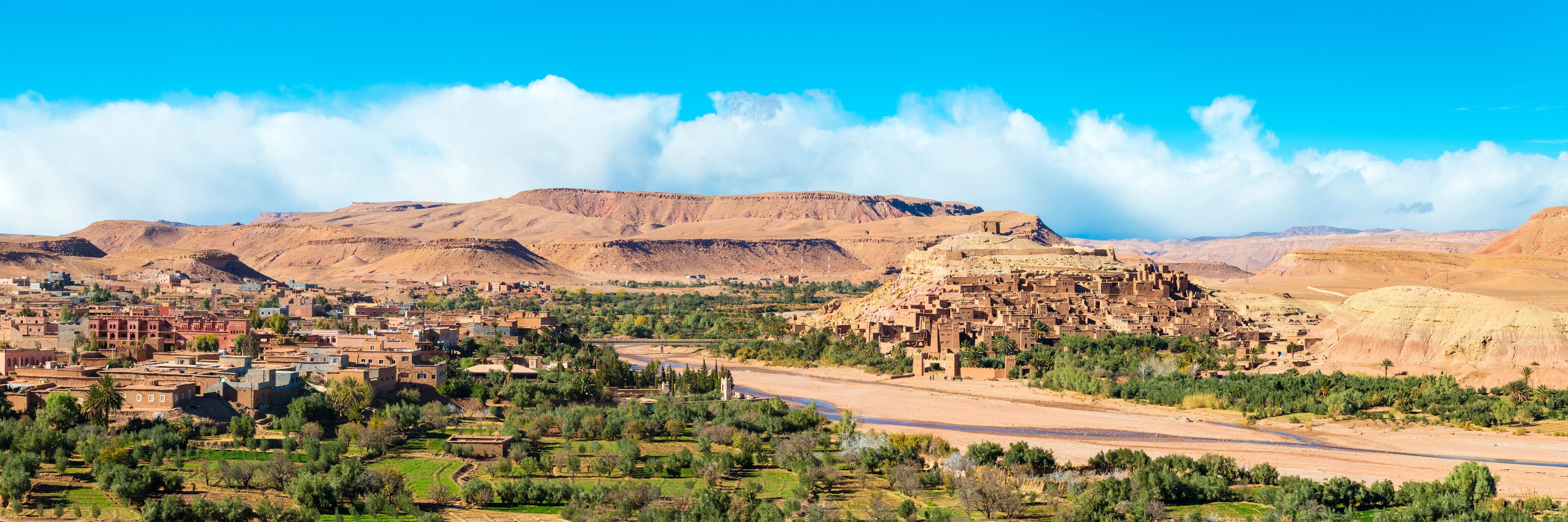 A desert landscape with a small town, mountains, and a river.