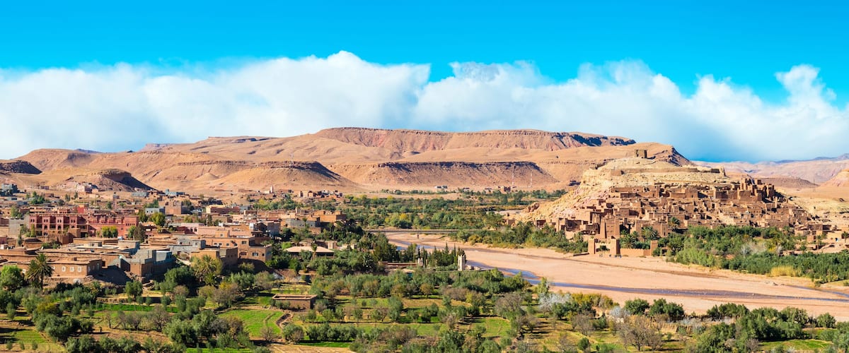 A desert landscape with a small town, mountains, and a river.
