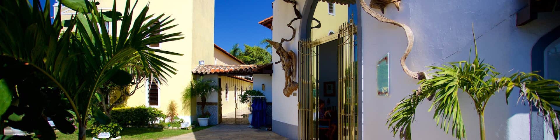 A courtyard with a stone floor, a building with a white facade and a red-tiled roof, and a statue of an angel.