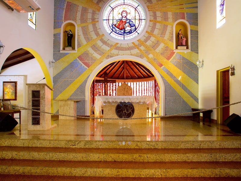 A church interior with a mosaic ceiling, a central altar, and a statue of Jesus.