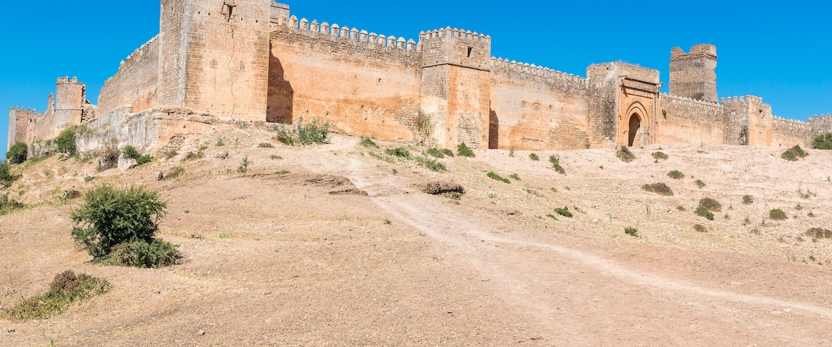 A historic stone fortress with crenellated walls and a prominent entrance gate.
