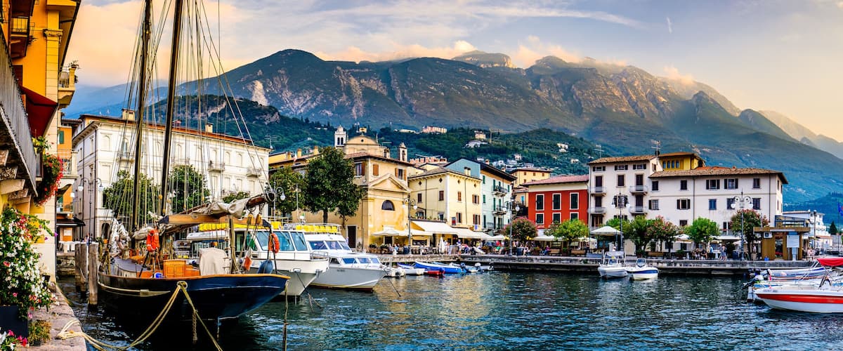 A harbor with boats, colorful buildings, and a mountain in the background.