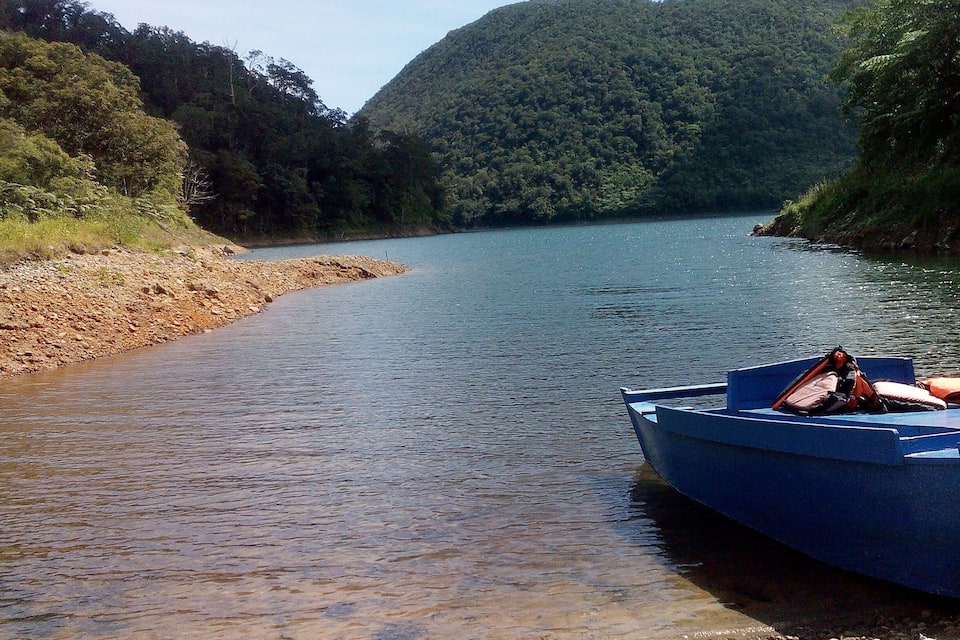Une rivière paisible où un bateau est amarré sur la rive, entourée de collines boisées.
