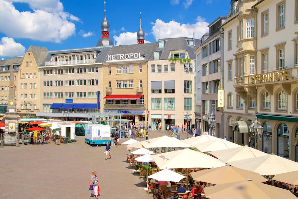 A bustling square with cafes, a market, and a prominent Metropol building.