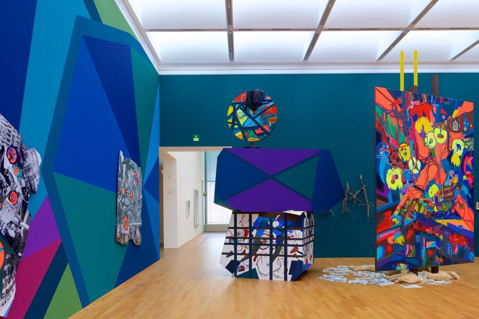 Een kunstgalerie met kleurrijke abstracte schilderijen en een moderne sculptuur.
