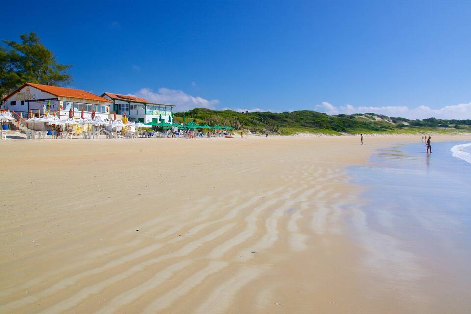 A beach with a building and umbrellas.