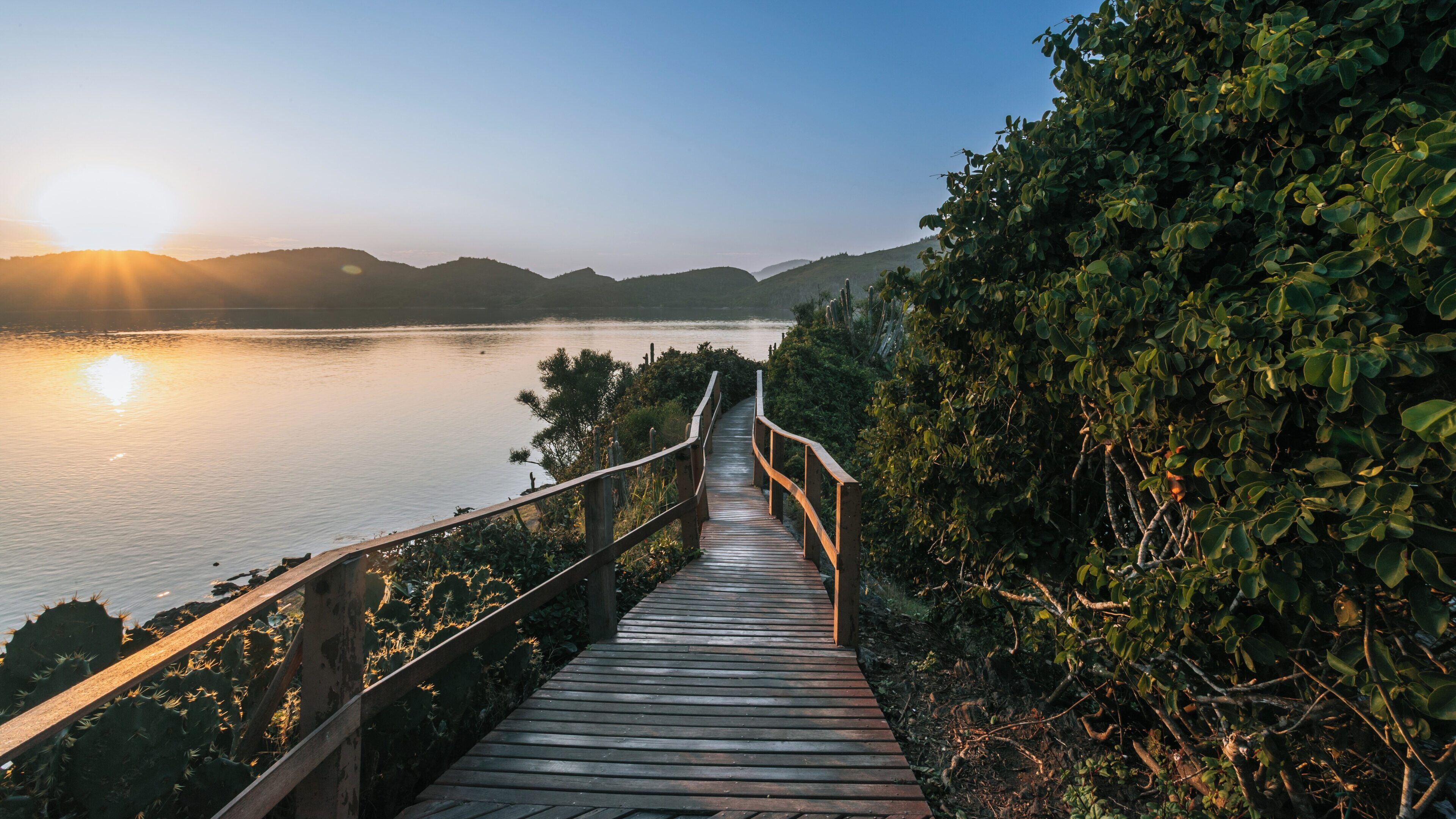 Explore the serene beauty of Arpoador Mount in Buzios on a calm morning at sunrise with reflections on the water