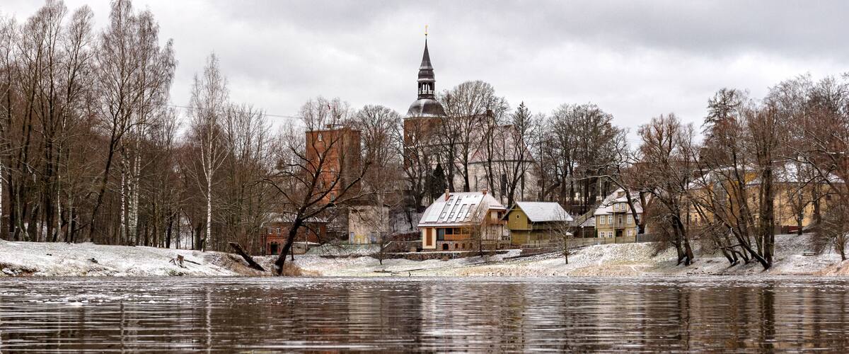 winter landscape with a river flowing, light snow covering the river banks, city panorama in the background