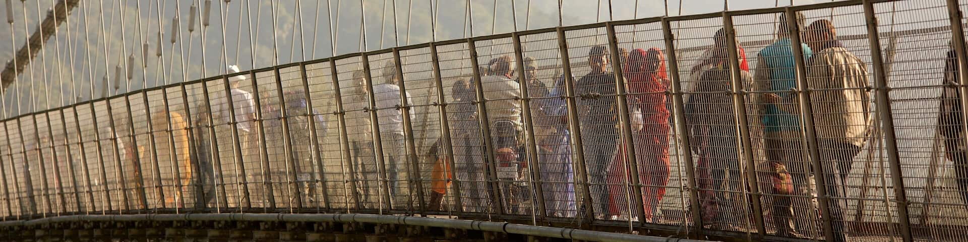 Ram Jhula featuring a suspension bridge or treetop walkway as well as a small group of people