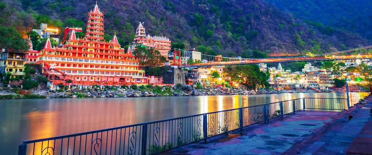 River Ganges, the famous bridge Laxman Jhula surrounded by temples and mountains around in rishikesh, India