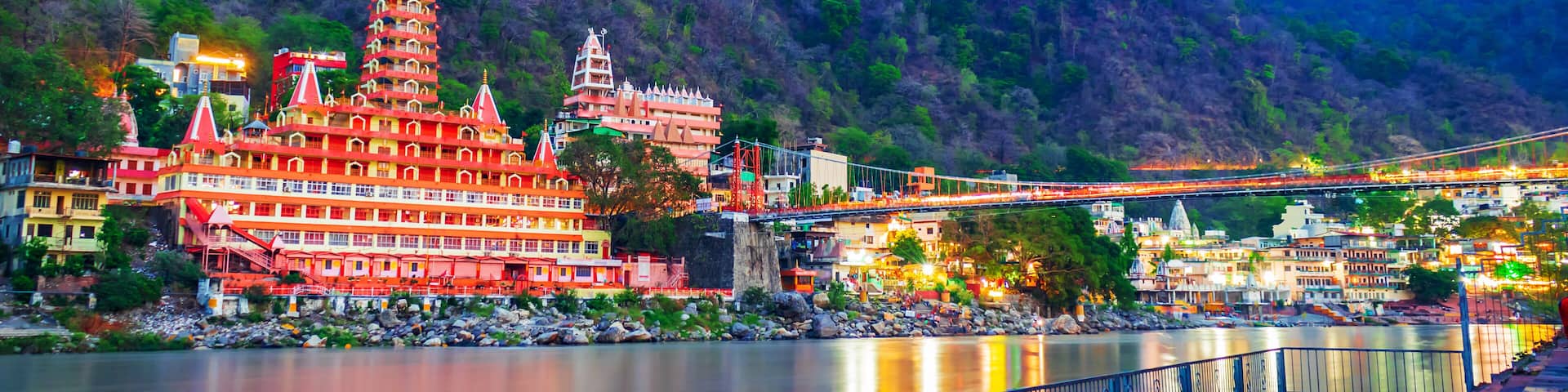 River Ganges, the famous bridge Laxman Jhula surrounded by temples and mountains around in rishikesh, India