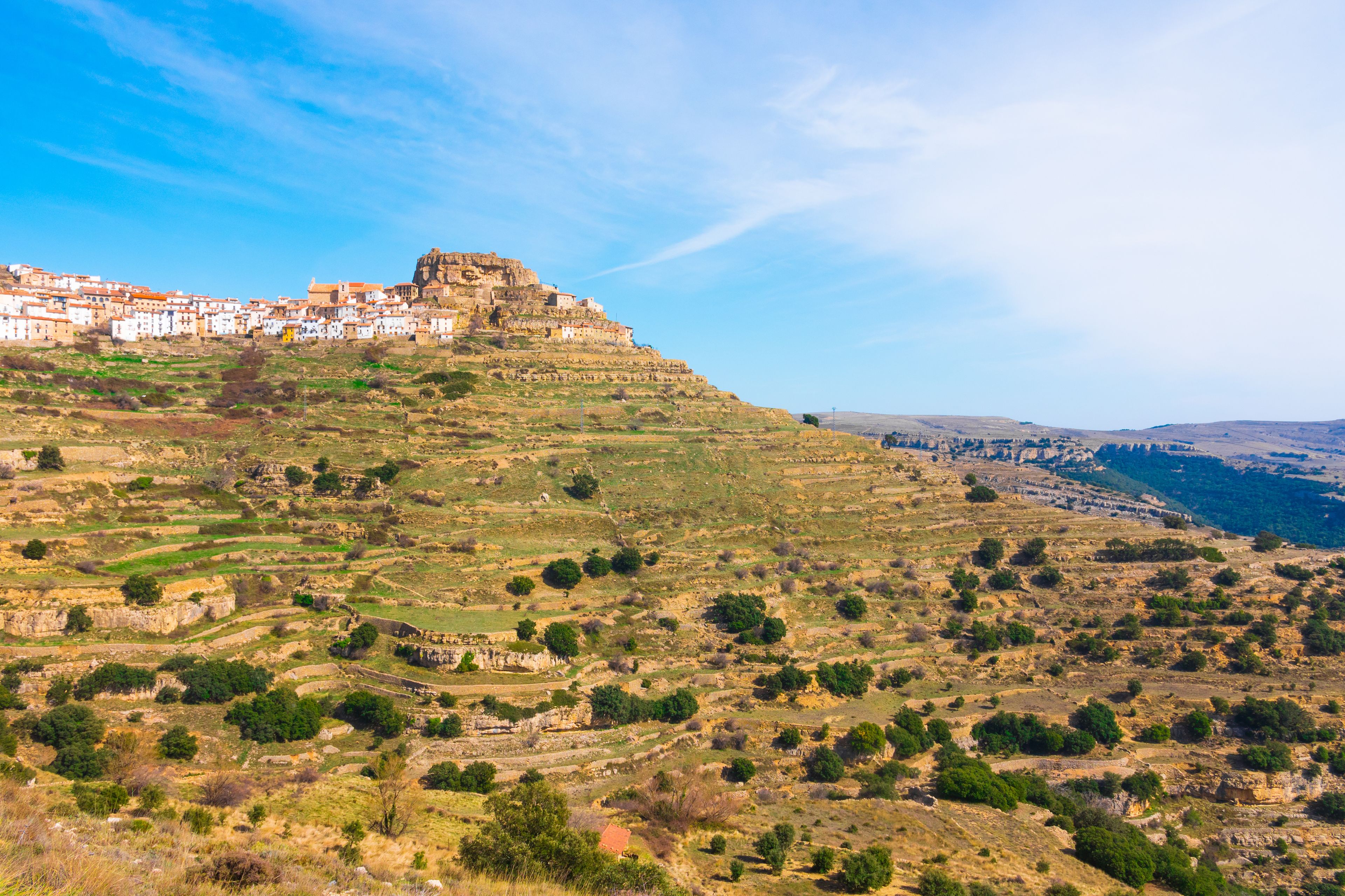 A hilltop town with terraced fields and a prominent castle-like structure.