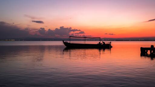 Sunset pier Albufera Valencia tourist ride boat reflections in the lake Natural Park Spain.