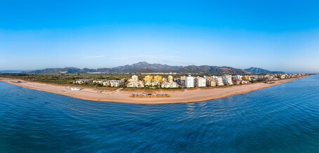 Eine Küstenstadt mit Strand, Gebäuden und Bergen im Hintergrund.