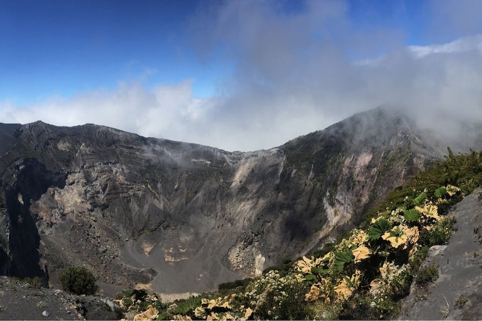 A mountainous landscape with a person standing on a ridge.
