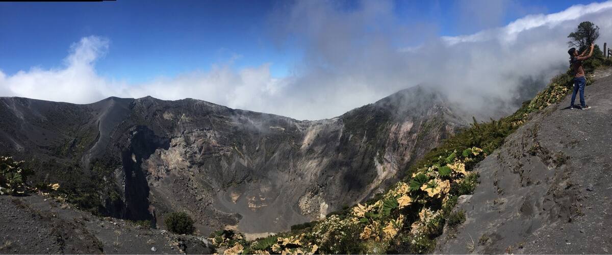 A mountainous landscape with a person standing on a ridge.