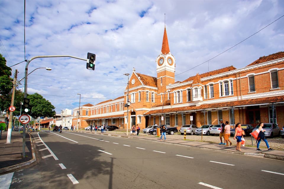 A street with a clock tower, cars, and pedestrians.