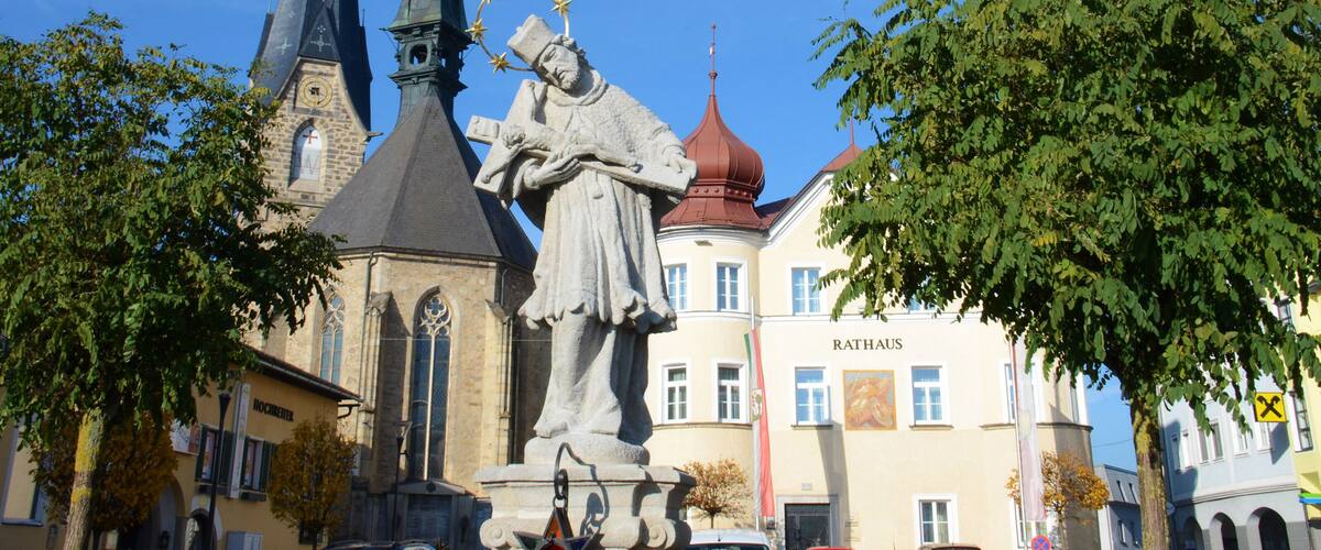A church with a tall spire, a statue, and a building with a red dome.