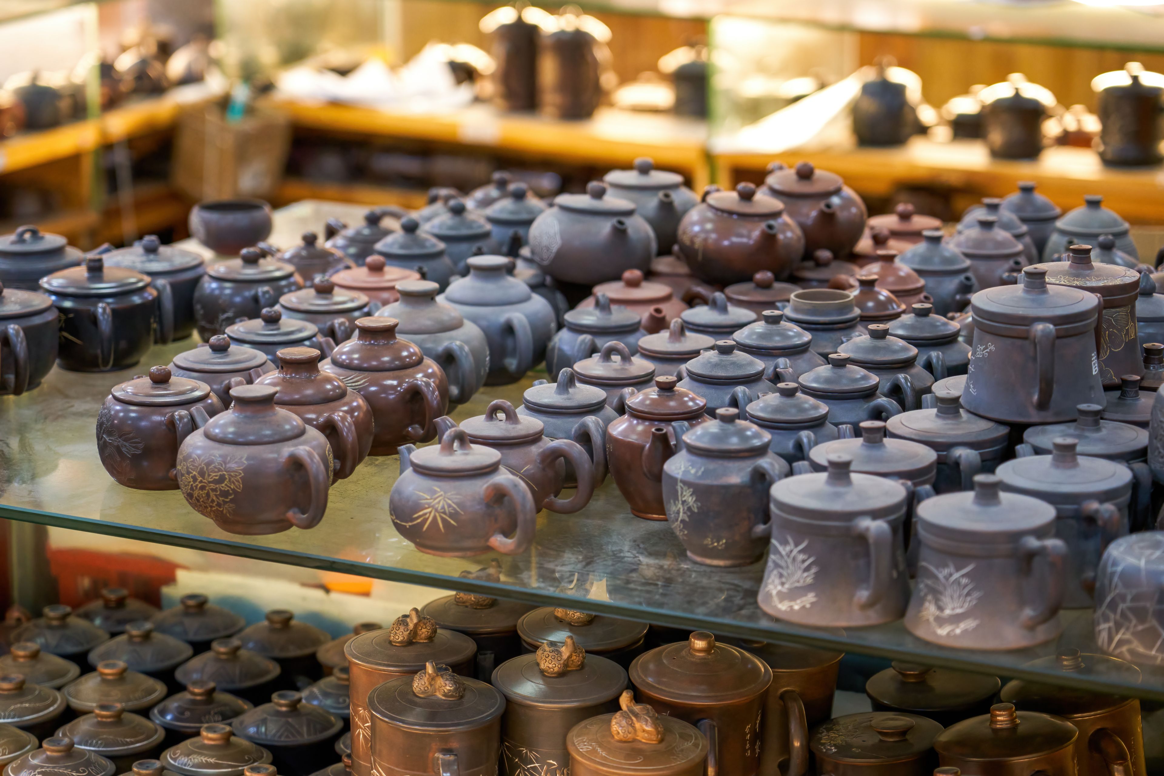 Una variedad de teteras y tazas de cerámica exhibidas en estanterías.