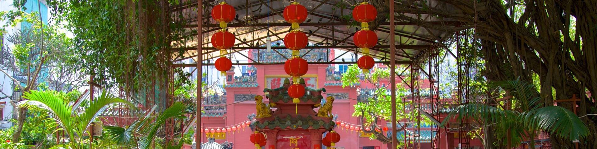 A traditional temple with red lanterns, a central ornate structure, and lush greenery.