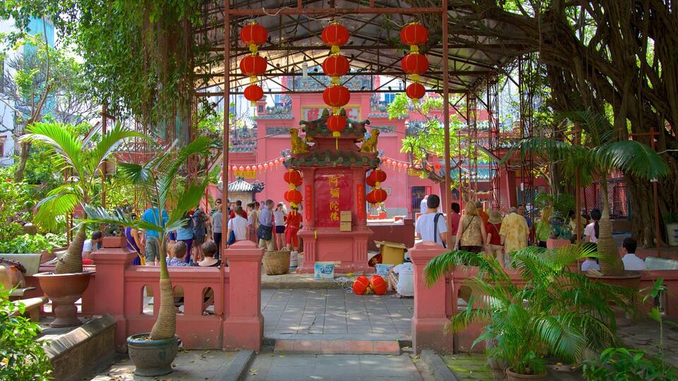 A traditional temple with red lanterns, a central ornate structure, and lush greenery.