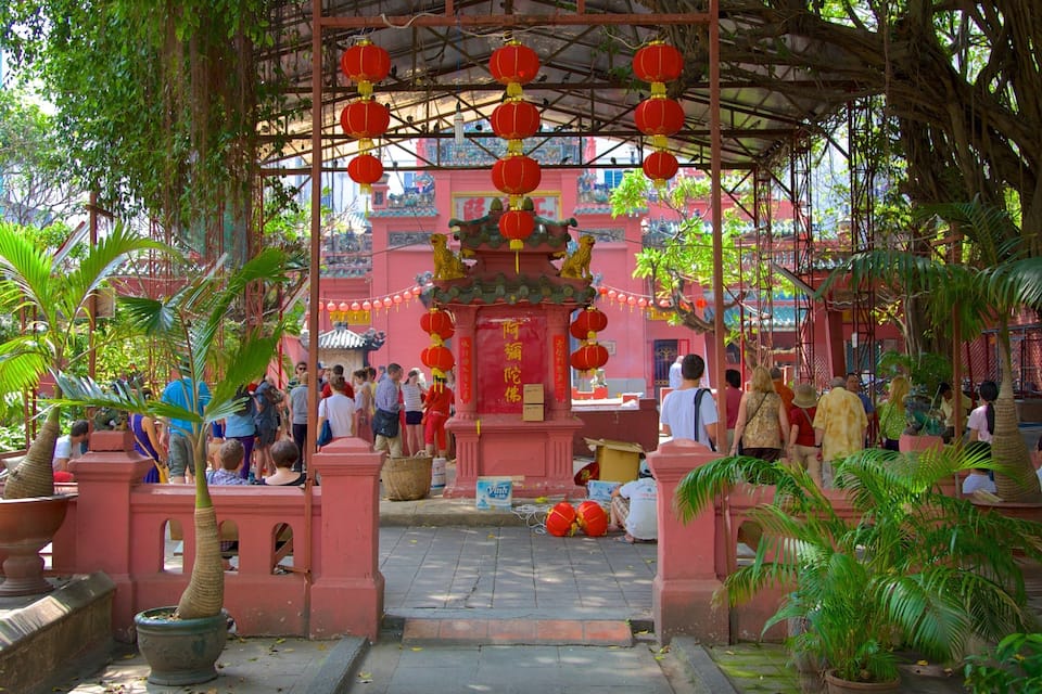 A traditional temple with red lanterns, a central ornate structure, and lush greenery.