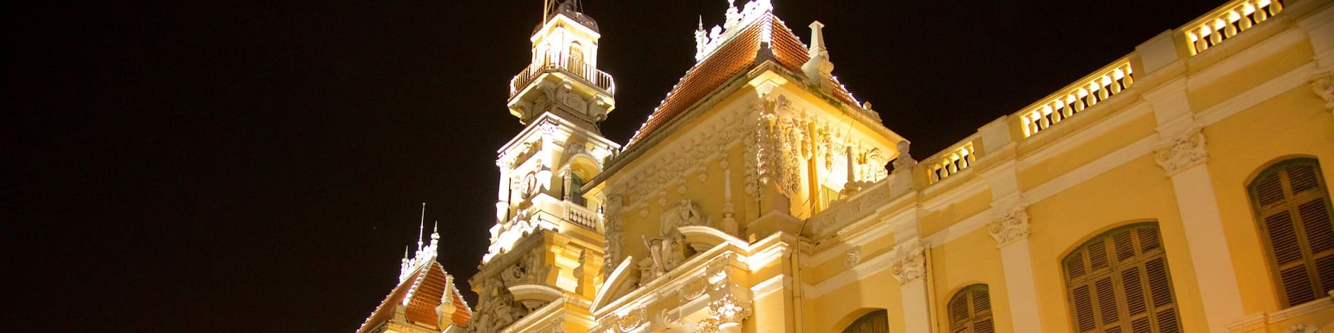 A grand, illuminated building with ornate architecture, including columns and decorative sculptures.