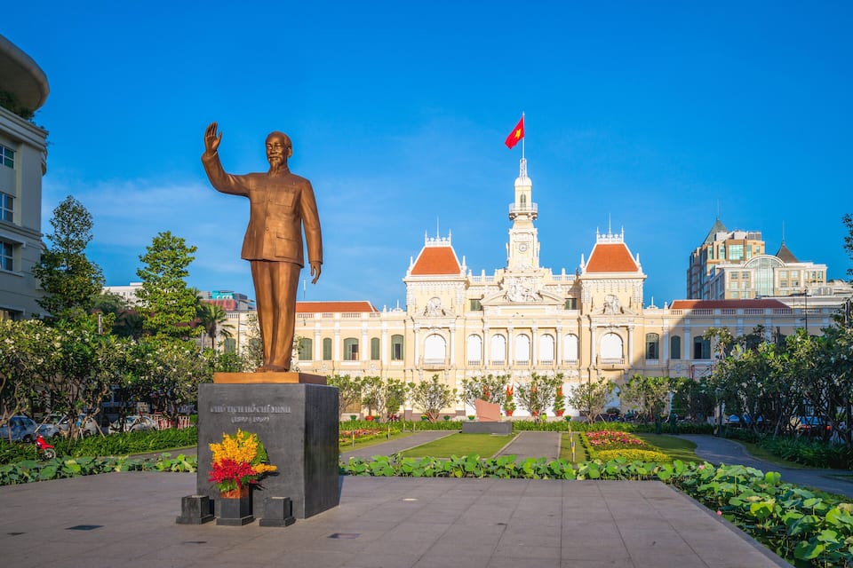 A statue in front of a grand building with a flag.