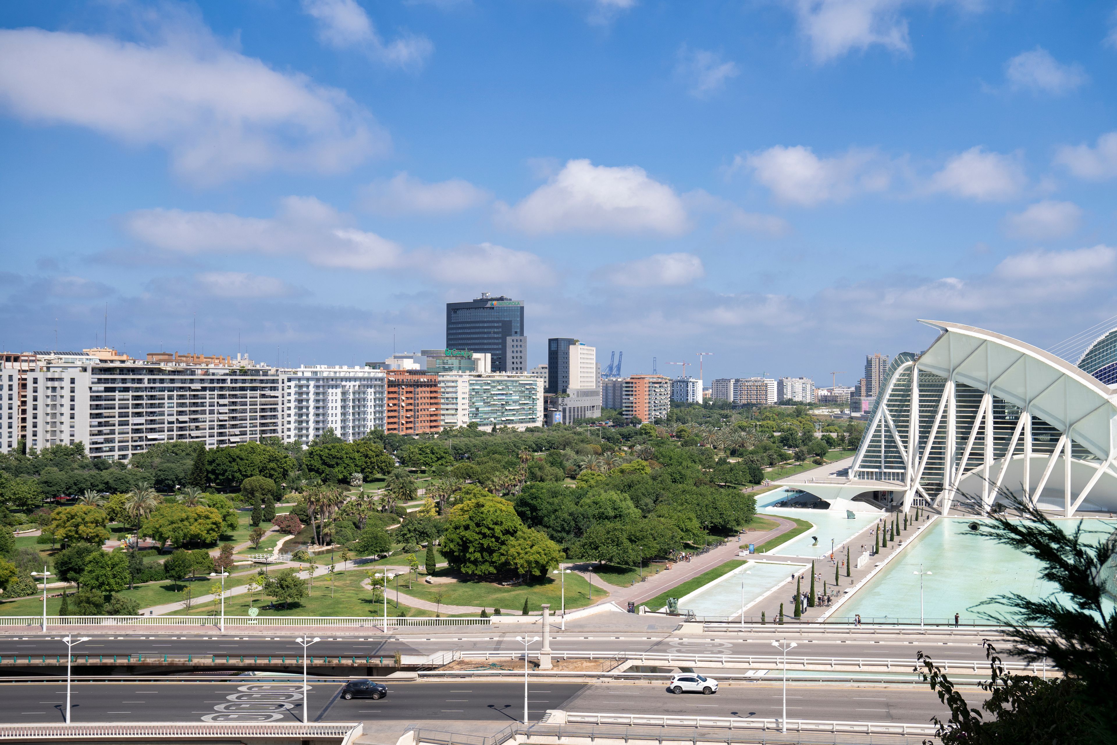 Un paisaje urbano con edificios modernos, un puente grande y un parque con árboles.