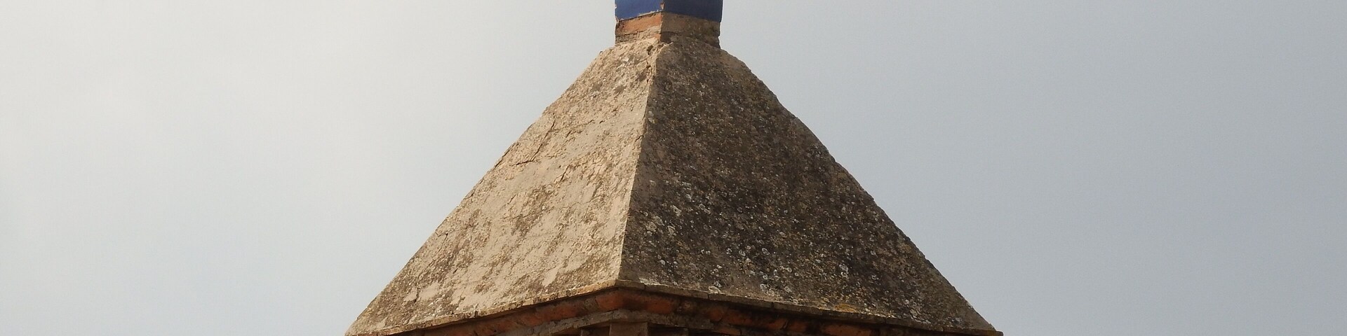 A tower with a pointed roof and a decorative finial.