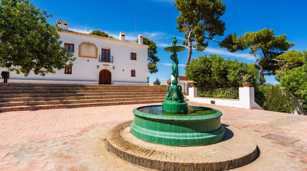 Une cour avec une fontaine, des marches menant à un bâtiment et des arbres.