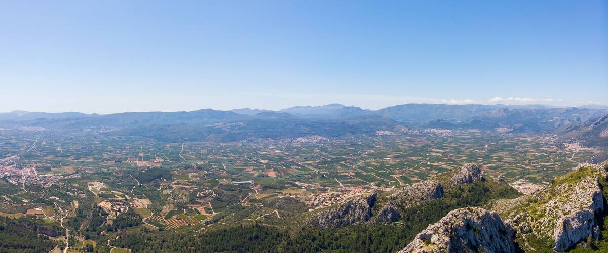 A mountainous landscape with a prominent peak, terraced fields, and a valley below.