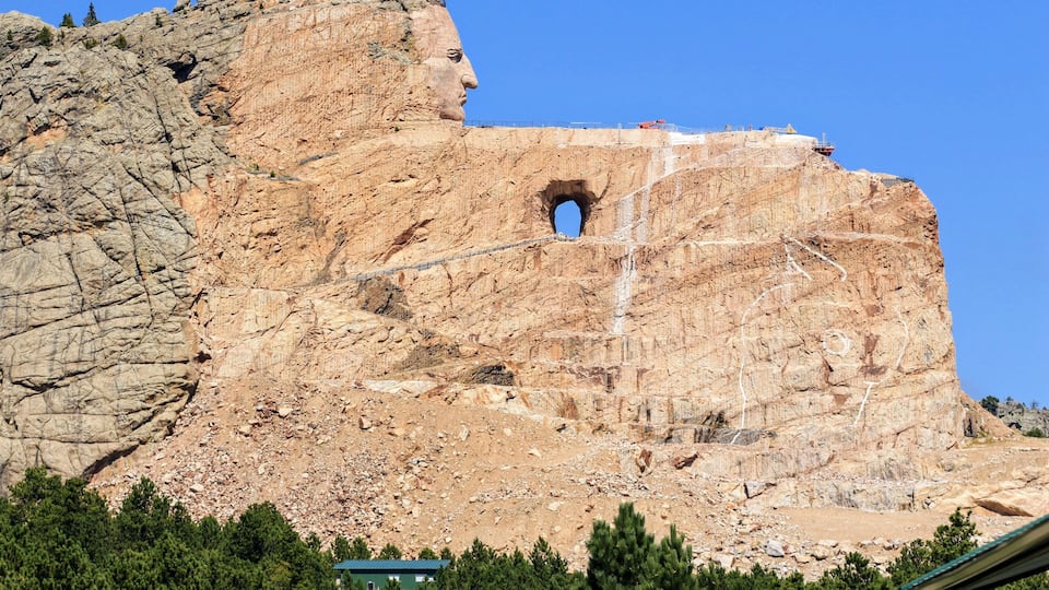 A large rock formation with a prominent archway and a small waterfall.
