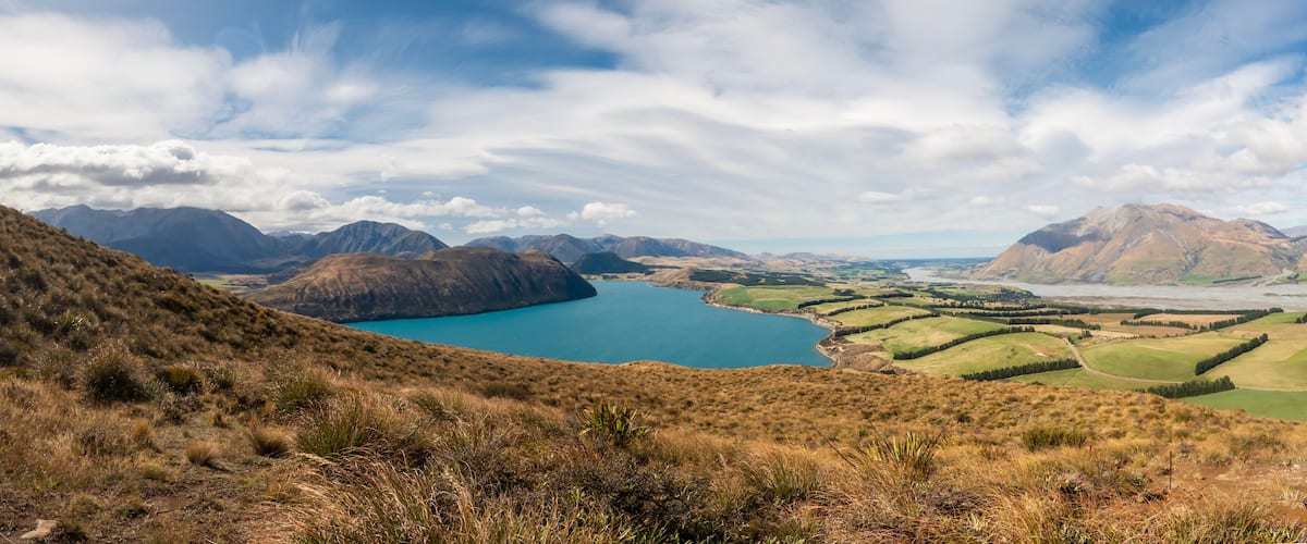 A mountainous landscape with a lake and green fields.