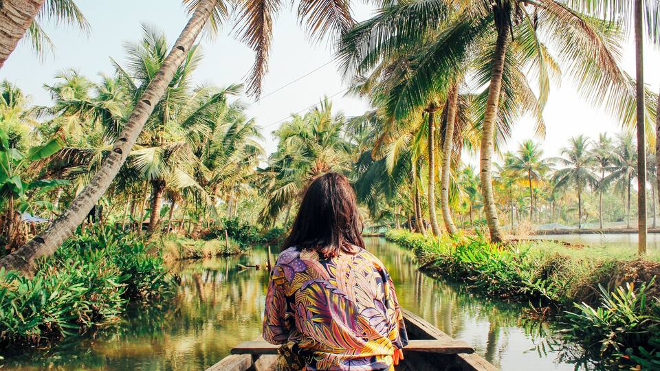 A river with palm trees and a boat.