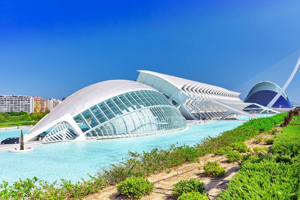 A modern architectural structure with a glass facade and a unique bridge design.