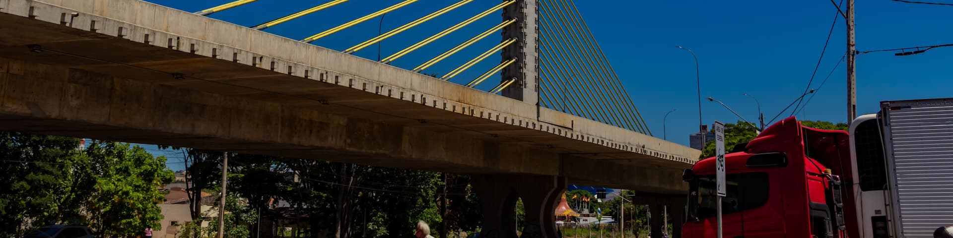 Viaduto Estaiado na cidade de Anápolis em Goiás. Viaduto com uma bandeira da cidade de Anápolis com céu azul ao fundo.