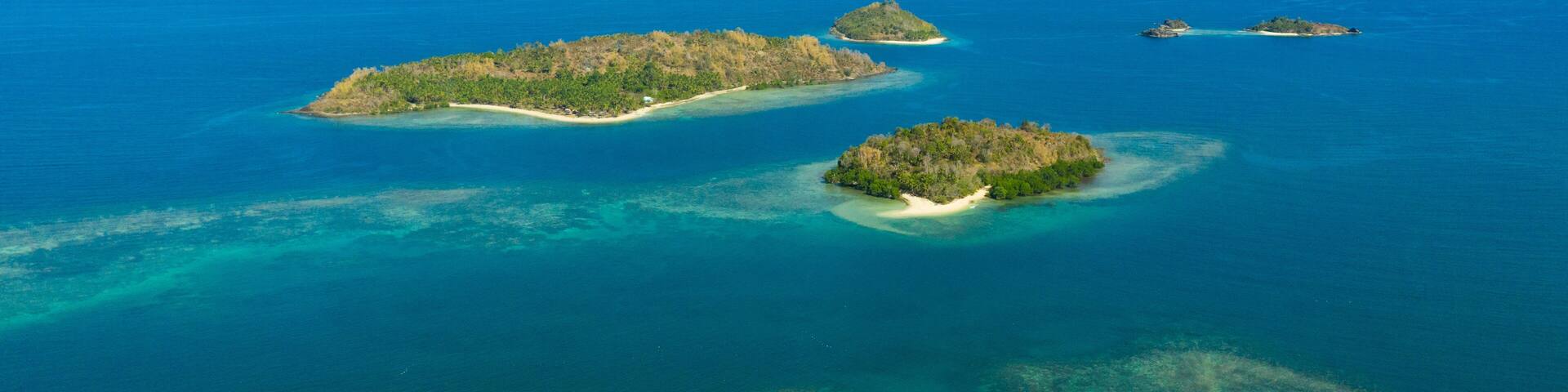 An aerial view of a chain of islands with clear blue waters and sandy beaches.
