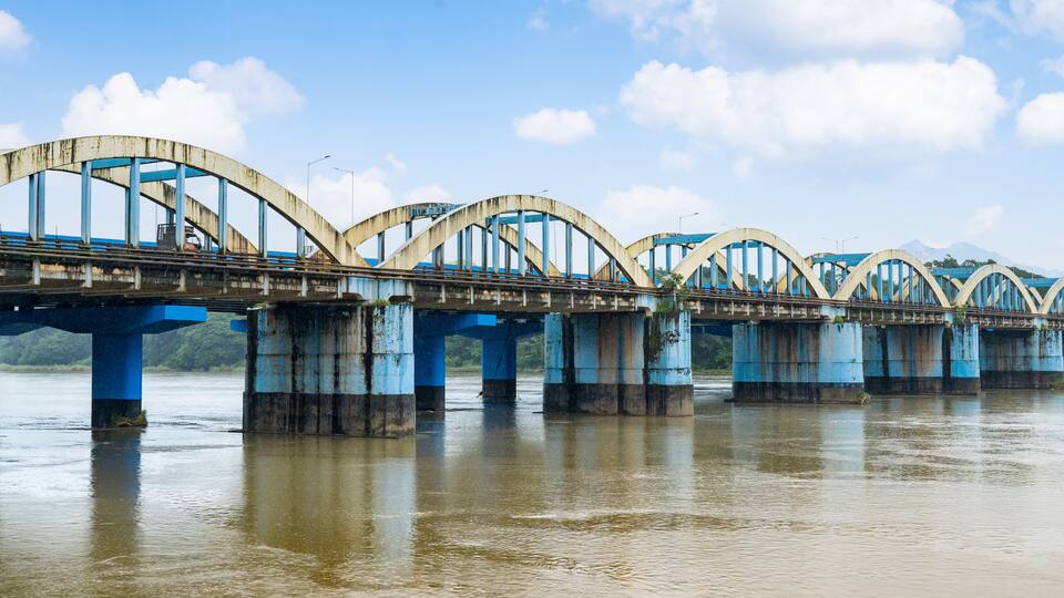 A large, arched bridge with blue supports over a river.