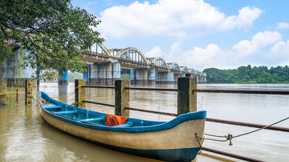 A blue boat tied to a dock with a bridge in the background.