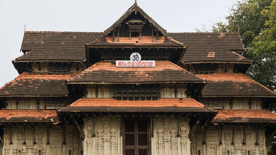 A traditional multi-tiered temple with ornate carvings and a red-tiled roof.