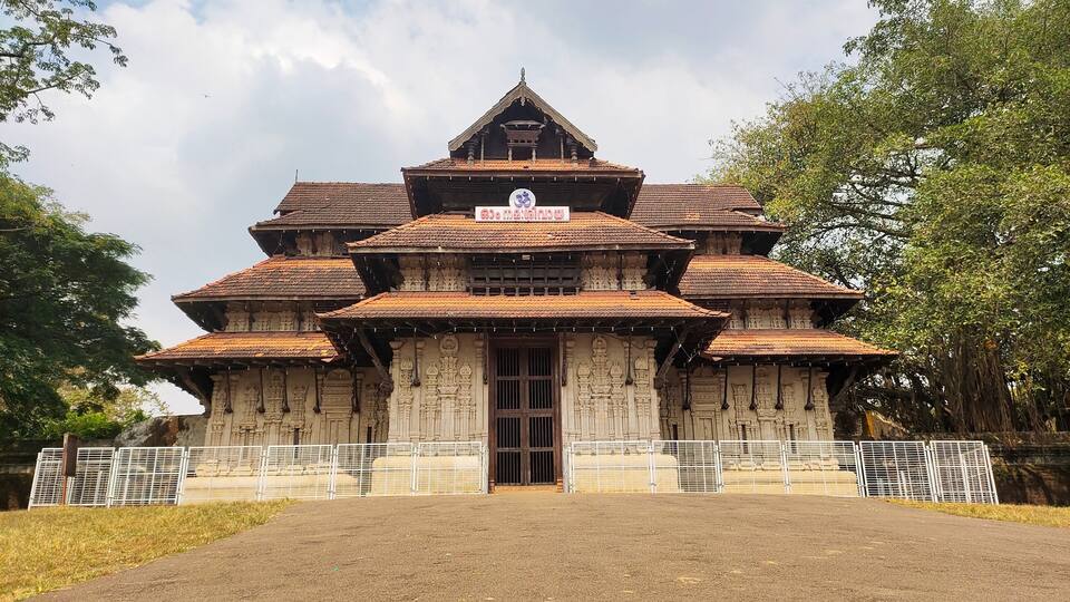 A traditional multi-tiered temple with intricate carvings and a signboard.