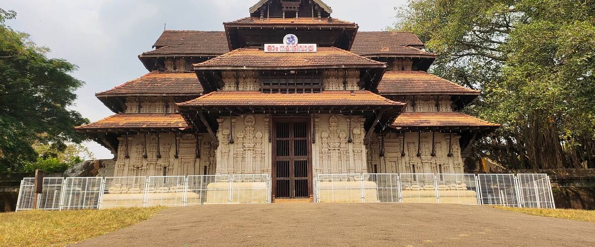 A traditional multi-tiered temple with intricate carvings and a signboard.