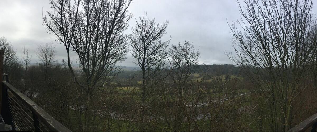 A balcony overlooking a rural landscape with leafless trees and a distant view of a village.