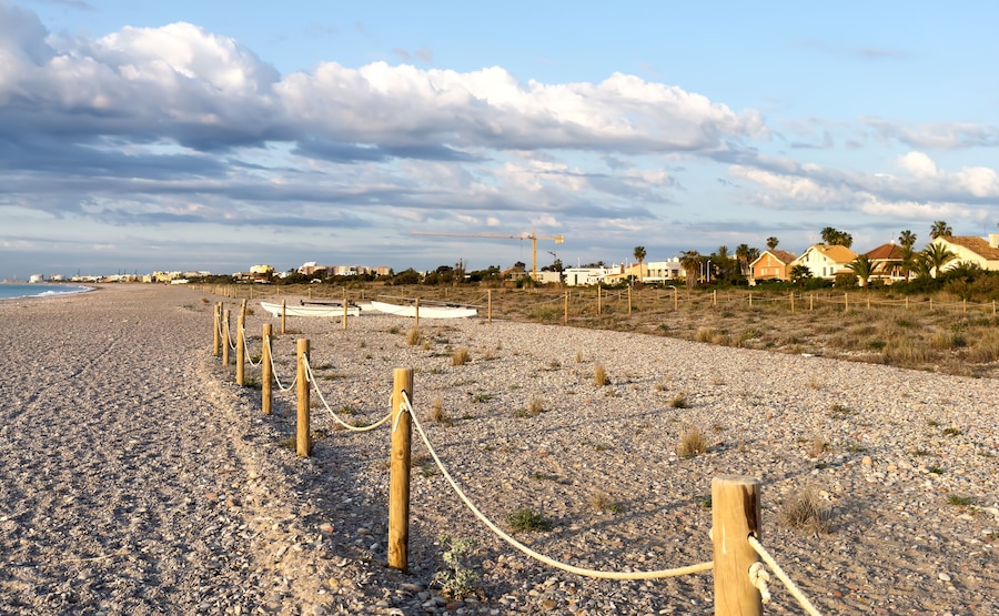 Pebble stone beach. Sea beach ocean shore. Coastline on empty pebble beach. Sea beach landscape. Coast pebbles. Shore landscape on Spain resort, Almarda. House on coastline. Waterfront vacation home