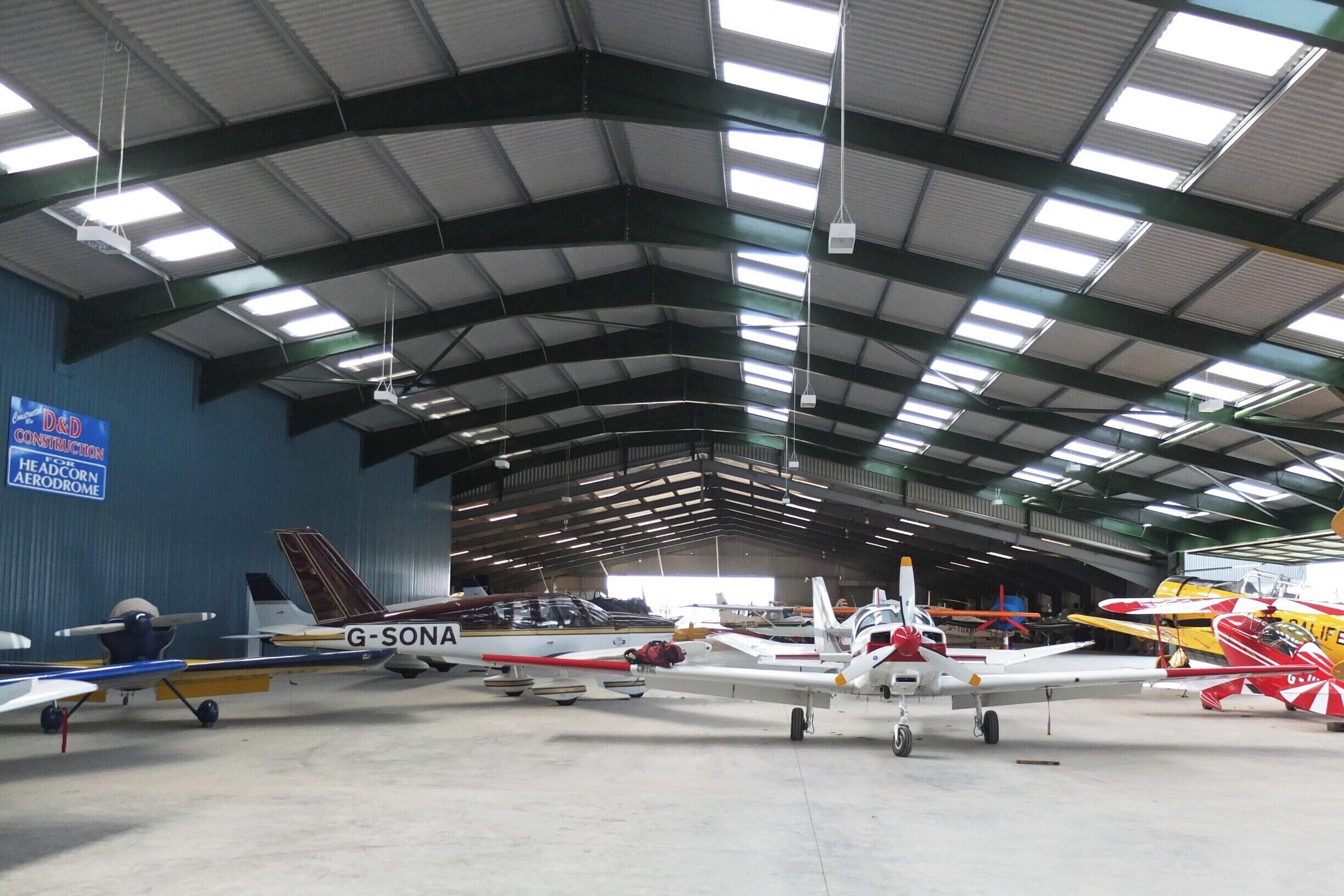 A hangar with multiple small aircraft parked inside.