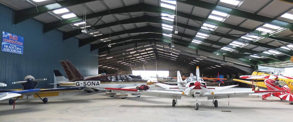 A hangar with multiple small aircraft parked inside.